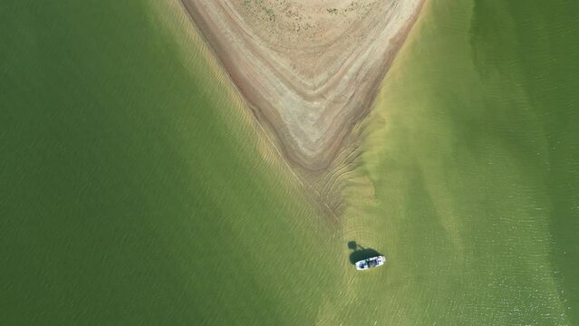 Aerial top view of the peninsula that washes the ocean, the waves wash the sandy shore, boat sailing on the sea.