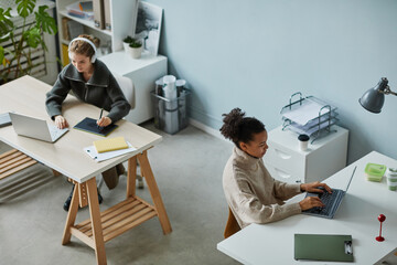 High angle view of young designers working on computers at desks at office