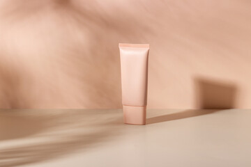 Cosmetic cream or mask in a white tube with hard shadows from the leaves on a white background....