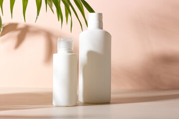 A set of women's professional cosmetics for face and body care. Cosmetic tube with skin care product on a beige background with palm leaves and shadows.