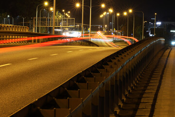 Autostrada samochodowa nocą ze smugami po przejeżdżających pojazdach. 