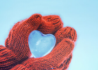 Female hands in knitted mittens with heart of snow in winter day. Love concept. Valentine day background.