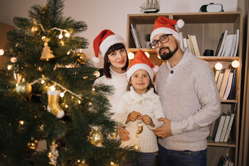 Family, winter holidays and people concept - happy father and little daughter decorating christmas tree at home.