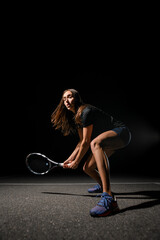 view on athletic woman standing in special pose with rocket ready to playing tennis.
