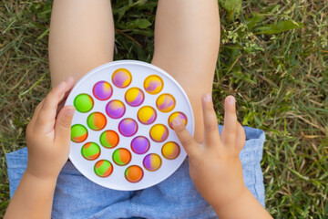 Colorful antistress sensory toy fidget push pop it in toddler's hands. Antistress trendy pop it...