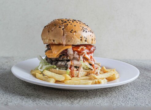 Double beef cheese burger with fries served in a dish isolated on grey background side view of fast food