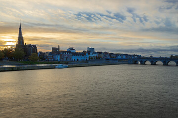 Fototapeta premium Maastricht, Netherlands 10-24-2022 Skyline of the Wyck area in downtown Maastricht with views on the iconic Servaas bridge and brewery. With a sunrise in Autumn coloring the sky in dramatic cloudscape