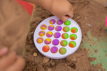 Colorful antistress sensory toy fidget push pop it in toddler's hands. Antistress trendy pop it...