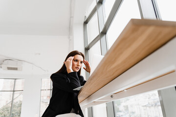 Sad girl with laptop got migraine touches her head because of pain. Woman manager with strong...