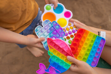 Colorful antistress sensory toy fidget push pop it in toddler's hands. Antistress trendy pop it...