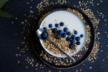 Yogurt, oatmeal, blueberries on a dark background