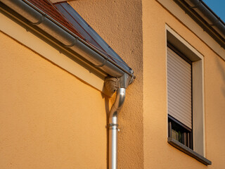 Wasp nest on a building exterior. The grey nest is hanging next to the roof gutter of a residential house. Destroying the insect home is very dangerous for humans. 