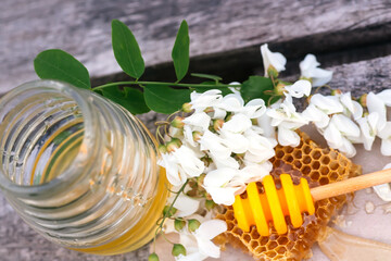 slice of fresh honey sat and bowl with yellow honeycomb with acacia flowers