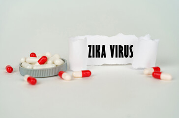 On a gray background, medical capsules and a paper plate with the inscription - Zika virus