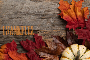 Naklejka na ściany i meble Thankful background mockup with colorful autumn leaves and pumpkin on wooden background. Thanksgiving. 