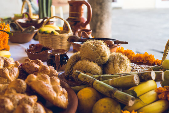Traditional Mexican Day of the Dead altar with offerings of cempasuchil marigold flowers, food and pan de muerto in Mexico for the holiday and cultural celebration, honoring and tradition