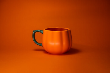 Pumpkin shaped coffee cup with orange background