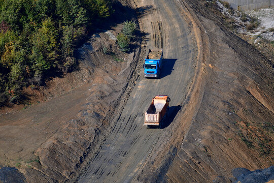 Large trucks transport excavated earth and rocks for highway construction