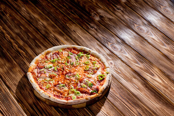 Delicious pizza with mozzarella cheese, ham, leeks on a tomato base on wood background