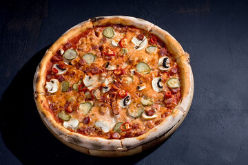 Appetizing pizza with hunting sausages, mozzarella cheese, pickled cucumbers, chili peppers on a tomato base. Mexican pizza. Top view