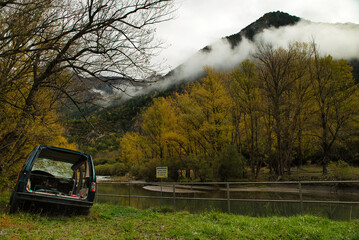 Old abandoned car found beside a lake in an autumn forest at dawn. Nature without garbage