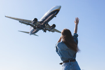 Girl and airplane in flight, landscape with woman standing with hands raised up, waving arms and flying passenger airplane, female tourist and landing commercial aircraft, summer sunny day