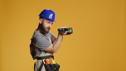 Portrait of repairman builder using electric power drill machine to work on renovation and...