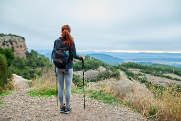 Ginger tourist with ski sticks enjoying the view