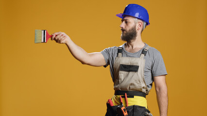 Handyman builder working with paintbrush to renovate walls and do refurbishment work with painting tools. Construction worker using brush to color and renovate space in studio.