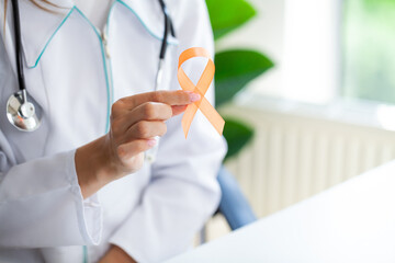 Doctor holding and showing orange awareness ribbon in her hands