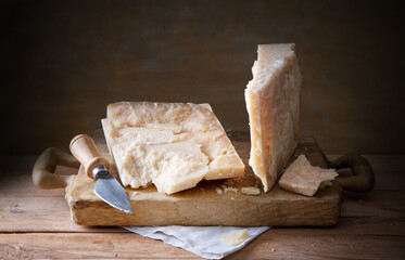 Pieces of parmesan with hard cheese knife on wooden cutting board, space for text, close-up. - Powered by Adobe