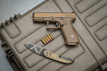 A coyote-brown pistol and a tactical folding knife.
