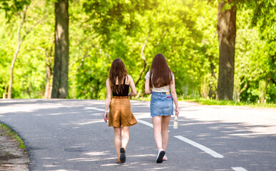 Two girlfriends walk along a path in the Park
