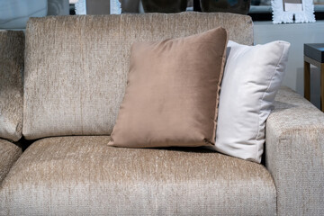 Close up light beige fabric sofa with warm cozy home interior background. Pillows on beige sofa room decoration background