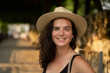 Beautiful young caucasic woman with a hat smiling to the camera in the streets of Spain