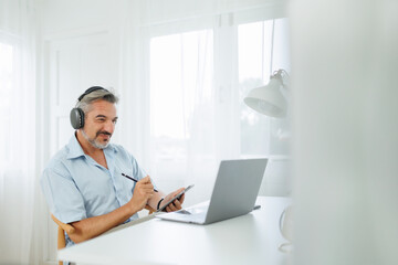 Senior adult Man in headphones using digital tablet and laptop