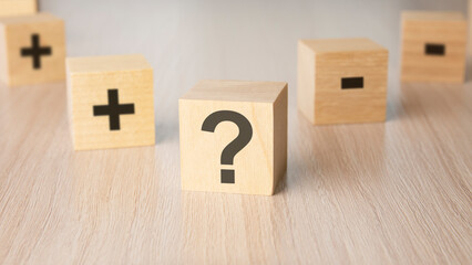 sign question mark, plus, minus sign on the faces of a wooden cube. mini wood cubes on wooden...