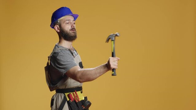 Construction worker using manual hammer to hit nails in wall, working with sledgehammer or mallet to break and wreck. Handyman doing rebuilding work with mechanical instrument and tools.