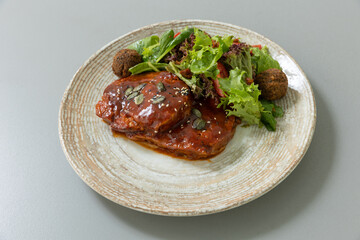 Meat with sauce served with mixed green salad