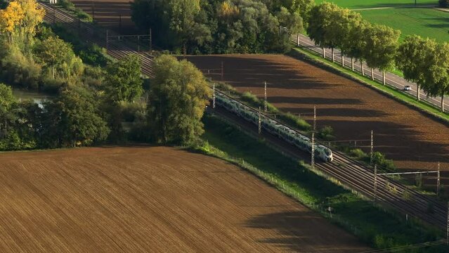 Country travel by high-speed train. Aerial view of fast passenger train driving on railroad. High angle view of Passing high speed train in rural summer country landscape