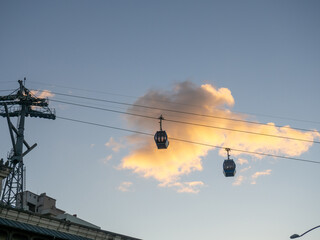 Ropeway. Esaltor booths against the background of a golden cloud.  Silhouettes of cable car cabins in the sky.