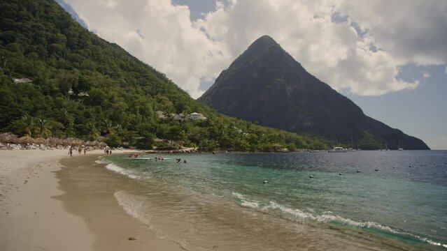 Panning shot of distant people and waves at ocean beach / St. Lucia