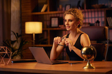 Purposeful young business woman, professional entrepreneur, works behind a laptop. Businesswoman, in a beautiful office in cinematic light. Finance, startups, stock trading, online work