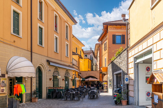A narrow side street of shops and sidewalk cafes in the colorful lakeside village of Menaggio, Italy, on the shores of Lake Como.
