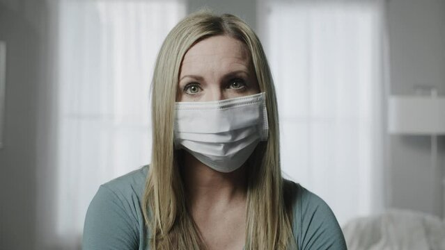 Close up portrait of woman wearing surgical mask looking at camera / Cedar Hills, Utah, United States