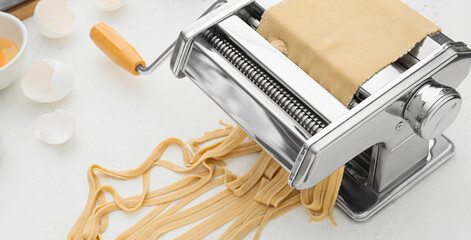 Pasta machine with dough on light background