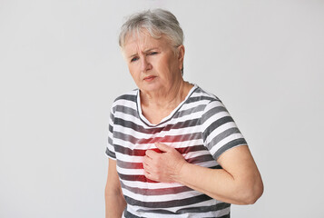 Senior woman having heart attack on grey background