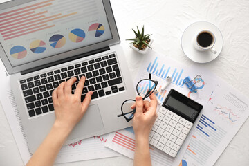 Woman working with business charts on laptop on light background