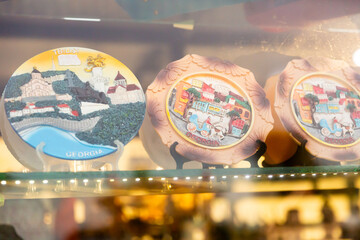 Various colorful hand-painted ceramic plates depicting tourist attractions on showcase of Georgian gift shop