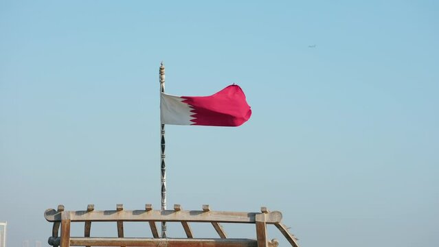 Elegant Qatar flag flying in the sky on a bright sunny day in slow motion on  a  dhow boat
